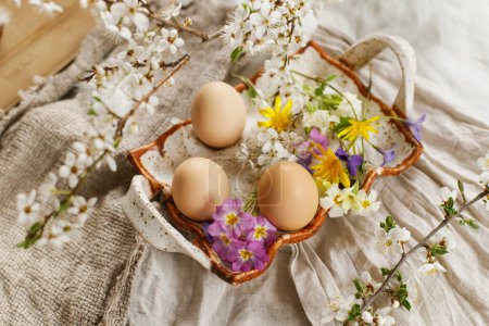 Téléchargez les photos : Joyeux Pâques ! Pâques rustique nature morte. Des œufs de Pâques élégants et des fleurs de printemps en fleurs sur fond de tissu de lin. Œufs naturels en plateau et fleurs sauvages - en image libre de droit