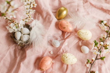 Photo for Happy Easter! Stylish easter eggs and blooming spring flowers on pink linen fabric. Modern eggs in nest, feathers and cherry blossoms. Rustic easter still life - Royalty Free Image
