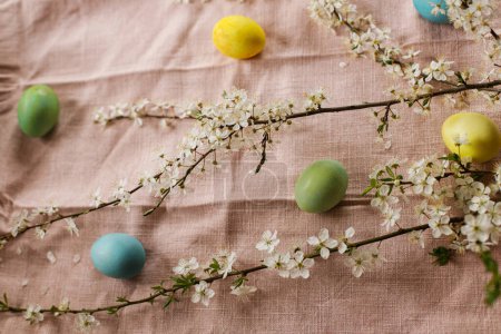 Foto de Stylish easter eggs and blooming cherry flowers on rustic table. Happy Easter! Rustic easter still life. Natural painted eggs and cherry blossoms on pink linen fabric - Imagen libre de derechos