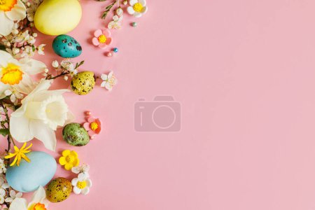 Foto de ¡Feliz Pascua! Huevos de Pascua con estilo y flores de primavera en flor sobre fondo rosa, espacio para el texto. Tarjeta de felicitación moderna o banner. Huevos coloridos pintados naturales y flor. Pascua naturaleza muerta - Imagen libre de derechos