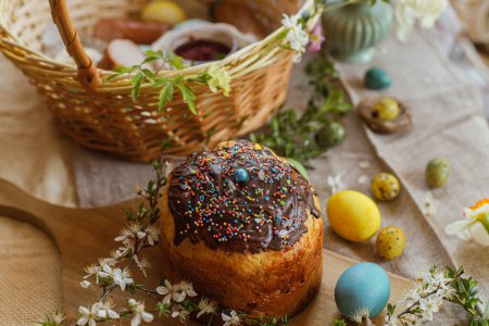 Foto de Natural dyed easter eggs and homemade easter bread on rustic table with spring blossoms and linen napkin. Top view. Traditional Easter food for basket - Imagen libre de derechos