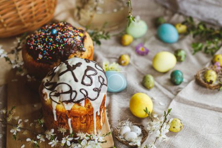 Téléchargez les photos : Pain de Pâques fait maison et œufs de Pâques teints naturellement avec des fleurs de printemps sur une serviette en lin sur une table rustique. Nourriture traditionnelle de Pâques. Joyeuses Pâques! - en image libre de droit