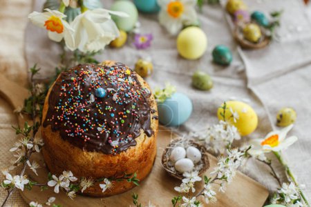Téléchargez les photos : Happy Easter! Homemade easter bread and natural dyed easter eggs with spring flowers on linen napkin on rustic table. Traditional Easter food. Top view - en image libre de droit