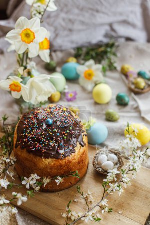 Téléchargez les photos : Happy Easter! Homemade easter bread and natural dyed easter eggs with spring flowers on linen napkin on rustic table. Traditional Easter food. Top view - en image libre de droit