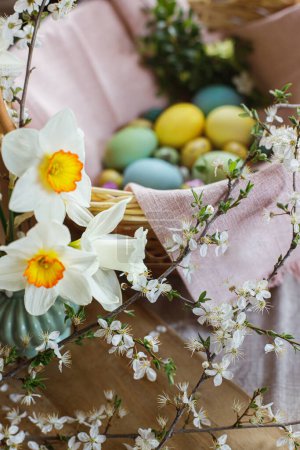 Foto de Beautiful daffodils on background of stylish natural dyed easter eggs with spring flowers on linen napkin in wicker basket. Rustic Easter still life. Happy Easter! - Imagen libre de derechos