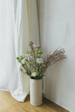 Photo for Modern bouquet in vase against tulle and rustic wall. Stylish spring flowers, eustoma, gypsophila and chamelaucium. Floral greetings, space for text. Happy women's day and mother's day - Royalty Free Image