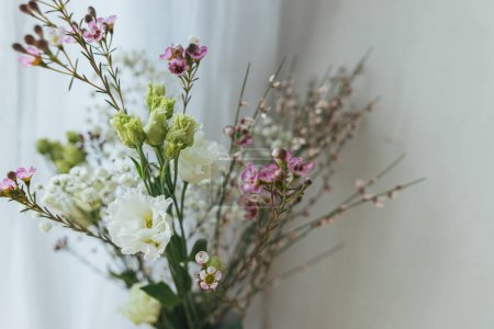 Photo for Stylish spring flowers, eustoma, gypsophila and chamelaucium on background of rustic wall. Floral greetings. Happy women's day and mother's day. Modern bouquet - Royalty Free Image