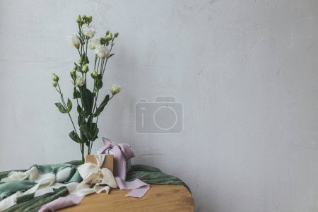 Photo for Stylish simple gift with silk ribbons and modern tender bouquet against rustic wall. Happy women's day and mother's day concept. Spring holiday still life. Greeting card, space for text - Royalty Free Image