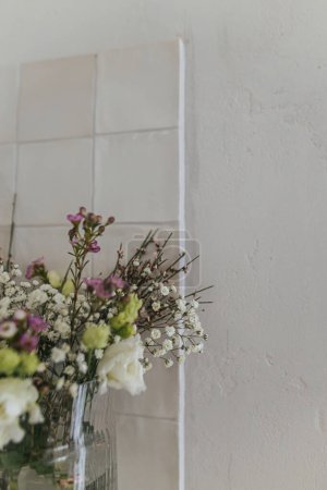 Téléchargez les photos : Stylish spring flowers, eustoma, gypsophila and chamelaucium on background of rustic wall. Floral greetings. Happy women's day and mother's day. Modern bouquet, space for text - en image libre de droit