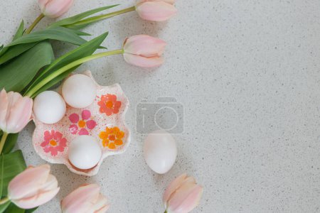 Téléchargez les photos : Belles tulipes et œufs naturels sur table moderne. Élégant Pâques plat couché avec espace de copie. Joyeux Pâques ! Porte-œufs à la main avec tulipes roses - en image libre de droit