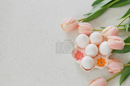 Photo for Beautiful tulips and natural eggs on modern table. Stylish easter flat lay with copy space. Happy Easter! Handmade egg holder with pink tulips - Royalty Free Image
