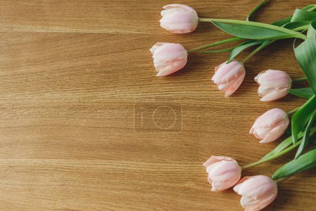 Photo for Beautiful tulips flat lay on wooden table with space for text. Modern easter decor. Stylish pink tulips bouquet. Happy mothers day and womens day - Royalty Free Image