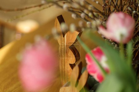 Photo for Stylish bunny and tulips on wooden table close up. Happy Easter! Tulips and willow branches bouquet with easter decor in dining room in farmhouse. Rustic arrangement - Royalty Free Image