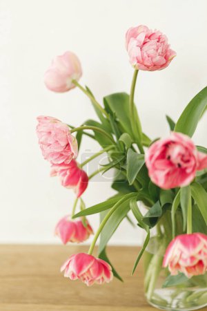 Téléchargez les photos : Élégant bouquet de tulipes dans un vase sur une table en bois dans une pièce rustique. Arrangement festif floral dans une ferme. Composition des fleurs printanières. Joyeuse fête des mères et des femmes - en image libre de droit
