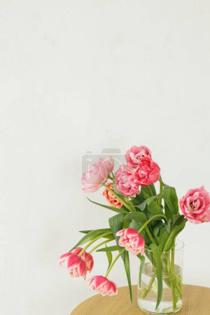 Photo for Stylish beautiful pink tulips bouquet in vase on wooden table in rustic room. Floral arrangement in farmhouse. Spring flowers composition, copy space. Happy mothers day and womens - Royalty Free Image