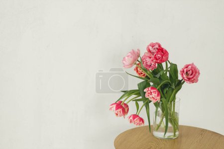 Foto de Elegante hermoso ramo de tulipanes rosados en jarrón sobre mesa de madera en habitación rústica. Arreglo floral en granja. Composición de flores de primavera, espacio de copia. Feliz día de las madres y las mujeres - Imagen libre de derechos