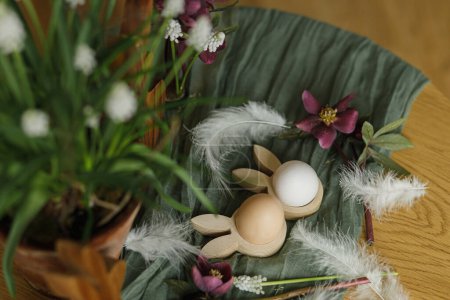 Téléchargez les photos : Pâques nature morte. Élégantes oreilles de lapin en bois et des œufs naturels, fleurs de printemps, plumes et nid sur la table rustique fermer. Joyeux Pâques ! Aménagement festif et décor dans une ferme - en image libre de droit