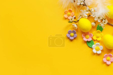 Téléchargez les photos : Stylish Easter eggs, colorful candy flowers and cherry blossoms flat lay on yellow background with copy space. Happy Easter! Greeting card template. Modern spring banner - en image libre de droit
