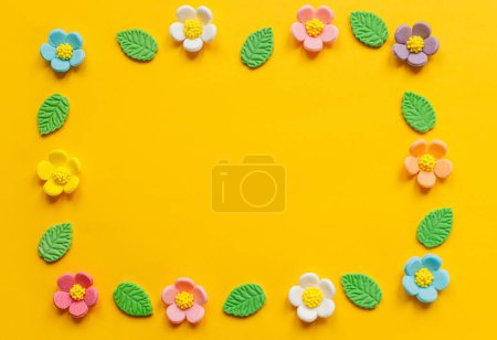Téléchargez les photos : Élégantes fleurs colorées plat posé sur fond jaune. Modèle moderne de fête avec espace de copie. Composition printanière. Bonbons doux fleurs et feuilles dans le cadre. Joyeux Pâques ! Carte de voeux - en image libre de droit