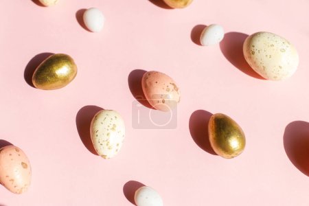 Foto de Elegantes huevos de Pascua a la luz del sol plana ponen sobre fondo rosa. ¡Feliz Pascua! Banner navideño moderno y tarjeta de felicitación. Composición de huevos de Pascua en luz soleada - Imagen libre de derechos