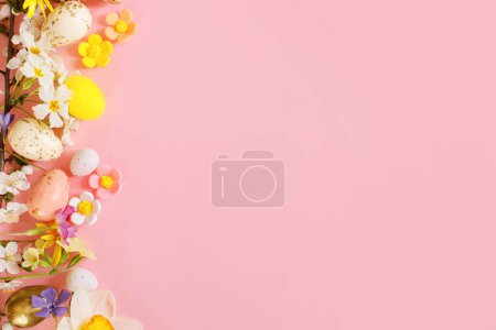 Téléchargez les photos : Des œufs de Pâques élégants, des fleurs de printemps, des fleurs de cerisier à plat reposent sur un fond rose avec un espace de copie. Joyeux Pâques ! Modèle de carte de vœux. Bannière de vacances moderne - en image libre de droit