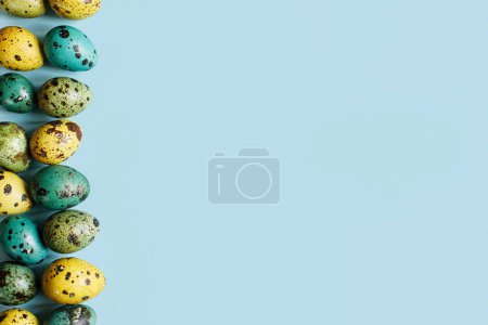 Téléchargez les photos : L'appartement de Pâques. Œufs de Pâques élégants sur fond bleu. Joyeux Pâques ! Naturel peint bordure oeufs de caille colorés, espace pour le texte. Carte de voeux moderne ou bannière - en image libre de droit