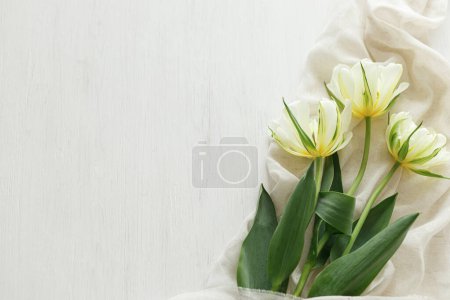 Foto de Hermosos tulipanes blancos con tela suave sobre mesa de madera rústica plana yacen con espacio para el texto. Feliz Día de las Madres. Ramo de primavera del jardín. Día de las mujeres - Imagen libre de derechos