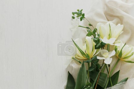 Foto de Hermosos tulipanes blancos y narcisos sobre tela suave sobre mesa de madera rústica plana con espacio para el texto. Feliz Día de las Madres. Elegante ramo de primavera del jardín. Día de las mujeres - Imagen libre de derechos