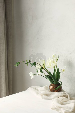 Foto de Hermosos tulipanes blancos y narcisos sobre mesa de madera contra pared rústica. Feliz Día de las Madres. Elegante ramo de primavera simple en florero vintage, bodegón floral. Día de las mujeres. Espacio para texto - Imagen libre de derechos