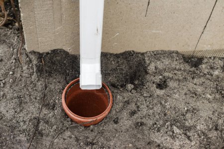 Photo for House gutter. Rainwater drainage system concept. White pipe for rainwater from roof on building and drain pipe in ground - Royalty Free Image
