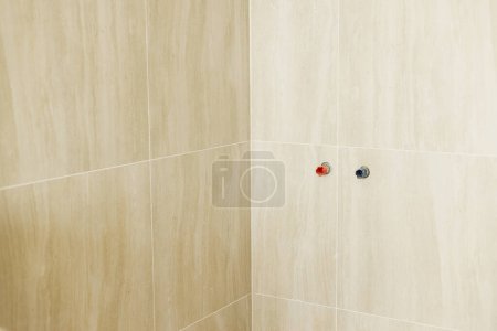 Foto de Tubería de agua en la pared y azulejos travertino en la pared y el suelo en el baño sin terminar. Construcción de la casa y el concepto de renovación del hogar. Tuberías de fontanería - Imagen libre de derechos