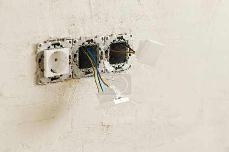 Téléchargez les photos : Boîte électrique avec prise et interrupteur. Installation d'un connecteur électrique dans un mur plâtré. Construction d'une maison et rénovation de la maison concept. Câblage - en image libre de droit