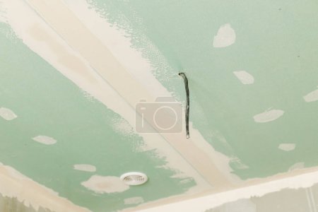 Téléchargez les photos : Plâtre plafond avec câbles électriques et ventilation dans la salle de bain inachevée. Construction d'une maison et rénovation de la maison concept. Gros plan du plafond baissé - en image libre de droit