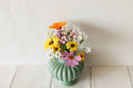 Photo for Stylish colorful wildflowers bouquet on tile shelf on rustic wall background. Beautiful summer flowers in vase gathered from garden, floral arrangement in modern room in home - Royalty Free Image