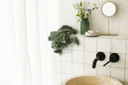 Téléchargez les photos : Belles fleurs dans la salle de bain moderne avec lavabo élégant, robinet noir et carreaux blancs. Arrangement de fleurs d'été recueillies du jardin dans la chambre moderne dans la maison - en image libre de droit