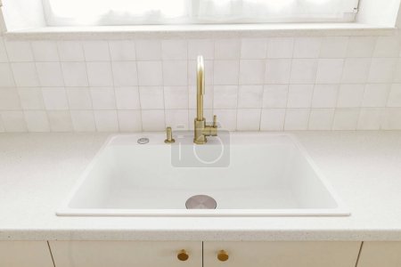 Photo for Modern minimal kitchen design. Stylish brass faucet and white granite sink, kitchen cabinets with knobs and granite counter in new scandinavian house.  Modern kitchen interior - Royalty Free Image