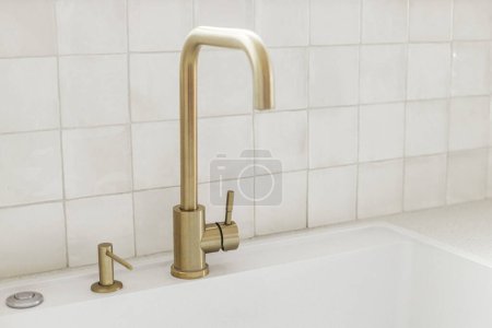 Photo for Stylish brass faucet and white granite sink on counter at window in new scandinavian house.  Modern kitchen interior. Modern minimal kitchen design - Royalty Free Image