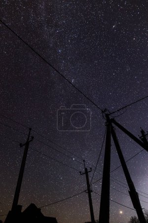 Foto de Increíble cielo nocturno con estrellas y torres de energía con líneas en el campo. Hermoso cielo estrellado y cables eléctricos - Imagen libre de derechos