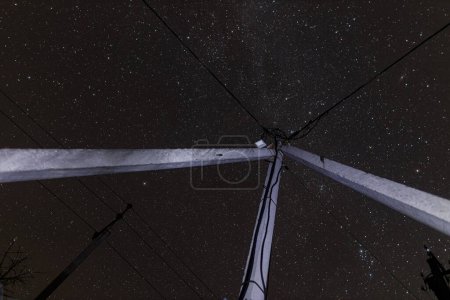 Foto de Increíble cielo nocturno con estrellas y torres de energía con líneas en el campo. Hermoso cielo estrellado y cables eléctricos - Imagen libre de derechos