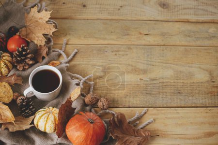 Foto de Warm cup of tea, pumpkins, fall leaves, cozy scarf on rustic wooden table flat lay with space for text. Hygge autumn template. Happy Thanksgiving. Fall still life banner - Imagen libre de derechos