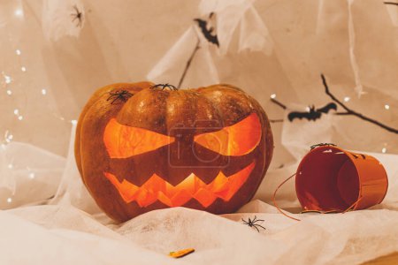 Foto de ¡Feliz Halloween! Spooky Jack o linterna calabaza tallada, telaraña, fantasma, murciélagos y luz brillante en la oscuridad. Espeluznantes decoraciones atmosféricas fiesta de halloween, espacio para el texto. Truco o trato - Imagen libre de derechos