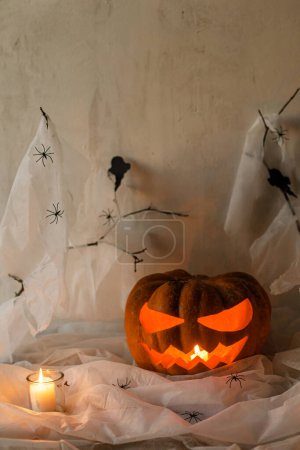 Foto de Spooky Jack o linterna calabaza tallada, telaraña, fantasma, murciélagos y velas brillantes en la noche. ¡Feliz Halloween! Espeluznantes decoraciones atmosféricas fiesta de halloween, espacio para el texto. Truco o trato - Imagen libre de derechos