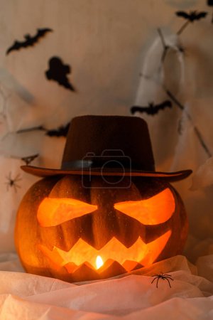 Téléchargez les photos : Joyeux Halloween ! Jack o lanterne sculptée citrouille, toile d'araignée, fantôme, chauves-souris et lumières incandescentes dans l'obscurité à l'intérieur. Spooky décorations atmosphériques d'Halloween avec des bougies dans la nuit. Trick ou traiter - en image libre de droit