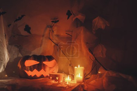 Foto de Spooky Jack o linterna calabaza tallada, telaraña, fantasma, murciélagos y luz brillante en la oscuridad. ¡Feliz Halloween! Espeluznantes decoraciones atmosféricas fiesta de halloween, espacio para el texto. Truco o trato - Imagen libre de derechos