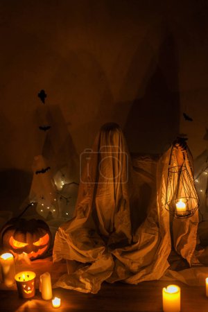 Foto de ¡Truco o trato! Fantasma aterrador sosteniendo linterna en la oscuridad. Decoraciones de Halloween atmosféricas de miedo y persona vestida de fantasma con calabaza brillante. Feliz Halloween! - Imagen libre de derechos