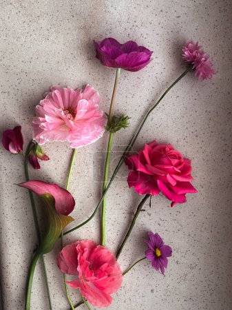 Photo for Beautiful pink rose, cosmos, poppy, sweet pea, cornflower flat lay on stone background. Stylish flowers still life in home, artistic composition. Floral vertical wallpaper - Royalty Free Image