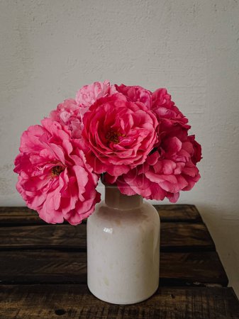 Photo for Beautiful pink roses in vase on rustic wooden background. Stylish flowers still life, artistic composition. Floral vertical wallpaper - Royalty Free Image