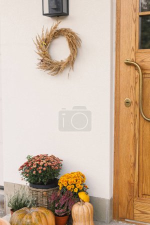 Foto de Corona rústica de otoño, calabazas y macetas en la puerta principal de madera. Elegante decoración otoñal de entrada de casa de campo o porche. Acuerdo de caída - Imagen libre de derechos
