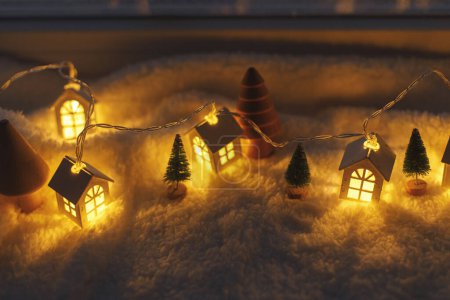 Téléchargez les photos : Village d'hiver miniature atmosphérique. Élégantes petites maisons lumineuses et des arbres de Noël sur une couverture enneigée douce dans la salle du soir. fond hygge de Noël. Joyeuses fêtes! - en image libre de droit