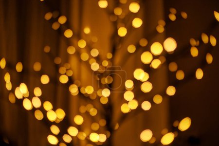 Téléchargez les photos : Noël flou lumières dorées bokeh. Bokeh de branches d'arbres modernes lumineuses minimes dans la salle confortable du soir, espace de copie. Joyeuses fêtes ! Illumination festive. Bannière de Noël - en image libre de droit